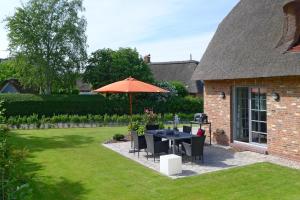 a table and chairs with an umbrella in a yard at Simons Hüs in Oldsum +13 photos
