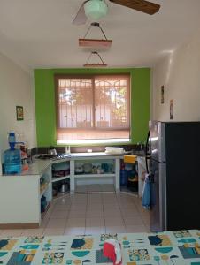 una cucina con pareti verdi, lavandino e frigorifero di Casa Miranda - Retalhuleu a Retalhuleu