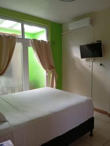 una camera da letto con un letto bianco e una finestra di Casa Miranda - Retalhuleu a Retalhuleu