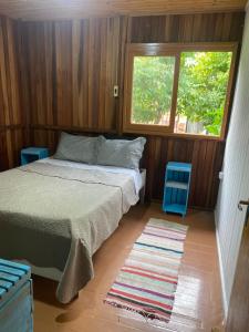 een slaapkamer met een bed, een raam en een tapijt bij Casa de campo in Passo De Torres