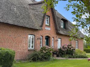 een oud stenen huis met een rieten dak bij De Utkieker in Witzwort