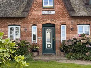 una casa in mattoni rossi con una porta verde di De Utkieker a Witzwort
