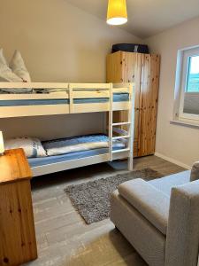 a bedroom with two bunk beds and a couch at Ferienhaus Schlossblick - ABC236 in Zierow