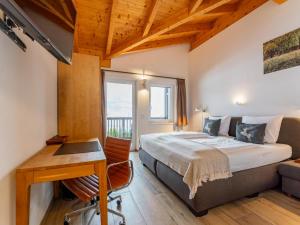 een slaapkamer met een bed, een bureau en een raam bij Salzach Lodge in Piesendorf