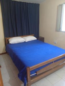 a bedroom with a bed with blue sheets and a window at Refugio Blue Hill I in Villa Cerro Azul
