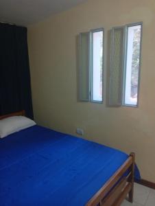 een slaapkamer met een blauw bed en 2 ramen bij Refugio Blue Hill I in Villa Cerro Azul