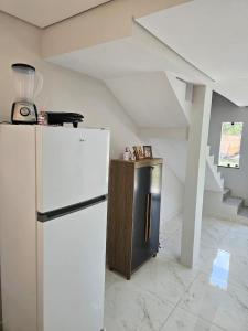 a kitchen with a white refrigerator and a staircase at Casa da Praia Bem Viver in Santa Cruz Cabrália