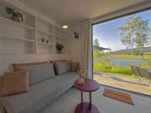 ein Wohnzimmer mit Couch und großem Fenster in der Unterkunft Feriendorf Seeblick - Tiny Chalet Nr 3 in Neunburg vorm Wald