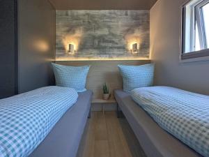 zwei Betten in einem Zimmer mit blauen Kissen in der Unterkunft Feriendorf Seeblick - Tiny Chalet Nr 6 in Neunburg vorm Wald