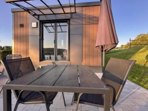 einen Holztisch mit Stühlen und einem Sonnenschirm auf einer Terrasse in der Unterkunft Feriendorf Seeblick - Tiny Chalet Nr 10 in Neunburg vorm Wald