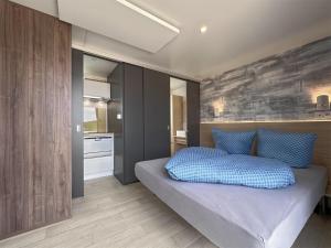 ein Schlafzimmer mit einem Bett mit blauen Kissen darauf in der Unterkunft Feriendorf Seeblick - Tiny Chalet Nr 10 in Neunburg vorm Wald