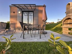 eine Terrasse mit Tisch, Stühlen und Sonnenschirm in der Unterkunft Feriendorf Seeblick - Tiny Chalet Nr 10 in Neunburg vorm Wald