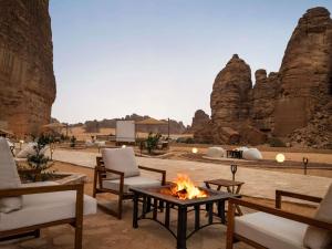 un patio con sedie e un fuoco davanti ad alcune rocce di Shaden Resort a Al Ula