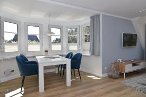 a dining room with a white table and blue chairs at Luv & Lee, Whg 10 in Westerland