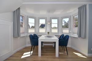 a dining room with a white table and blue chairs at Luv & Lee, Whg 10 in Westerland +12 photos
