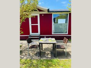 a table and chairs in front of a red house at Strandhaus James Cook Teichhof Fehmarn in Wenkendorf