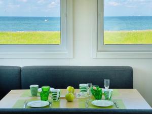 a table with plates and glasses on it with a view of the ocean at Strandhaus James Cook Teichhof Fehmarn in Wenkendorf