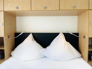 a bed with two pillows on top of it at Strandhaus James Cook Teichhof Fehmarn in Wenkendorf +33 photos