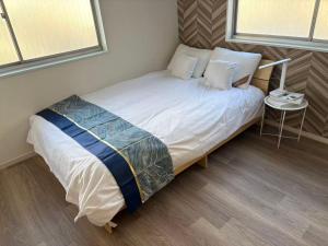 ein kleines Schlafzimmer mit einem Bett mit weißer Bettwäsche und Kissen in der Unterkunft 品闲居 in Osaka