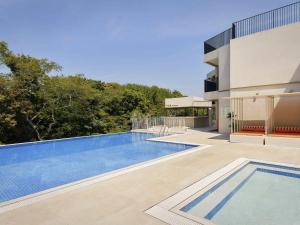 ein Swimmingpool vor einem Haus in der Unterkunft Mercure Ambassador Jeju in Seogwipo