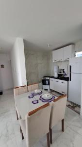 a kitchen with a table and chairs and a kitchen with white appliances at Apartamento em Jacumã in Conde