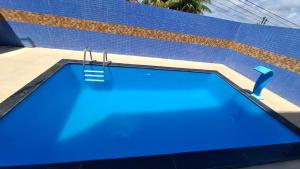 a blue swimming pool next to a blue wall at Apartamento em Jacumã in Conde
