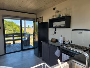 a kitchen with a stove and a view of a deck at Casa Esquila de Chiloé in Chonchi