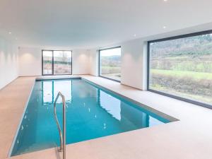 a swimming pool in a house with windows at Le Vol du Milan Premium villa with pool in Forrières