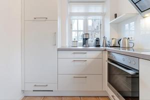 a kitchen with white cabinets and a window at Wynkaat in Nieblum