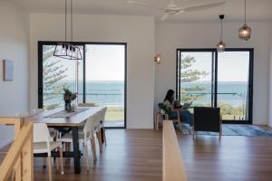 a dining room with a table and a woman sitting in a chair at Fairy Wren in Kingscote