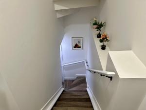a hallway with white walls and stairs with flowers at Sleek Guest Retreat SW EDM BSMT Suite in Edmonton +17 photos