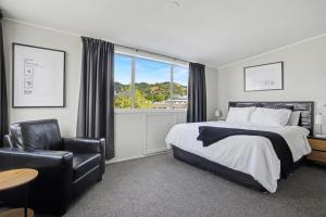 een slaapkamer met een bed, een stoel en een raam bij The Upper Rooms in Nelson