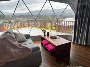 ein Wohnzimmer mit Couch und großem Fenster in der Unterkunft La cabaña de Ciela G glamping con jacuzzi y croquet in Latacunga