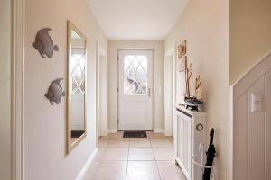 een hal met een witte deur en een spiegel bij Alte Eiche in Utersum