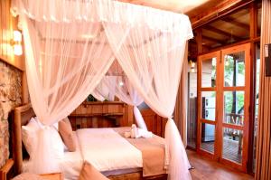 a bedroom with a canopy bed with white curtains at Eco Cabins Hideaway Ella in Ella