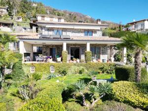 ein Haus auf einem Hügel mit Palmen und Büschen in der Unterkunft Villa with Panoramic Views in Oggebbio
