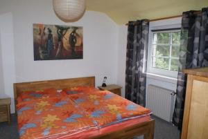 a bedroom with a bed with an orange comforter and a window at Am Hegehof - ABC181 in Lübstorf