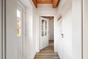 een gang met witte muren en een witte deur bij Strandnest in Witsum