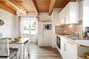 een keuken met witte kasten en een houten plafond bij Strandnest in Witsum +11 foto's