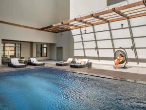a child sitting in a chair next to a swimming pool at Movenpick Hotel and Residences Riyadh in Riyadh