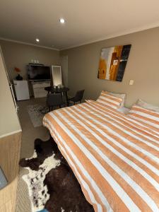 a bedroom with a large bed and a living room at Casa Miguelle a Private mini house in Dunedin