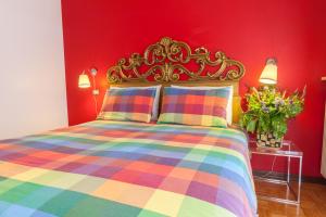 a bedroom with a colorful bed with a red wall at Toti Apartment in Udine