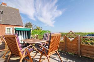 a table and chairs on a deck with a fence at Wodan, Whg 1 in Tinnum