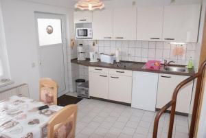 a kitchen with white cabinets and a table and a sink at Ferienhaus Albrecht - ABC207 in Wismar