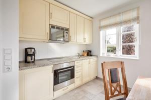 una cucina con mobili bianchi e un forno a piano cottura di Haus Kastanie a Boldixum Altre 19 foto