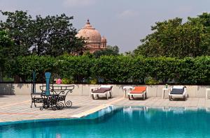 ein Pool mit Stühlen und ein Gebäude im Hintergrund in der Unterkunft Clarks Avadh in Lucknow