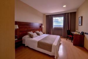a hotel room with a bed, chair, and a television at Sercotel Riscal in Puerto Lumbreras
