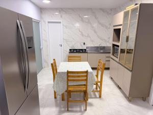 a kitchen with a table and chairs and a refrigerator at Recanto perto do mar com Jacuzzi in Camboriú