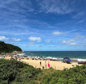 a group of people on a beach near the ocean at Recanto perto do mar com Jacuzzi in Camboriú
