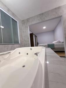 a white bath tub in a bathroom with a bedroom at Recanto perto do mar com Jacuzzi in Camboriú +11 photos